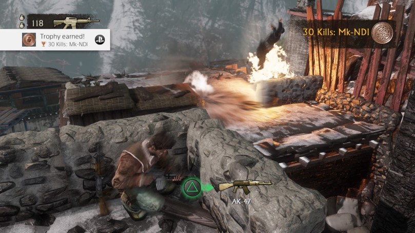 Nate hiding behind a wall and defeating enemies with grenades below him on a snowy road.