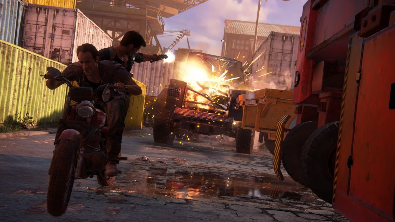 Sam and Nathan on a motorbike are chased by an armored and armed truck. Nathan is shooting at the truck, destroying its front that is catching fire.